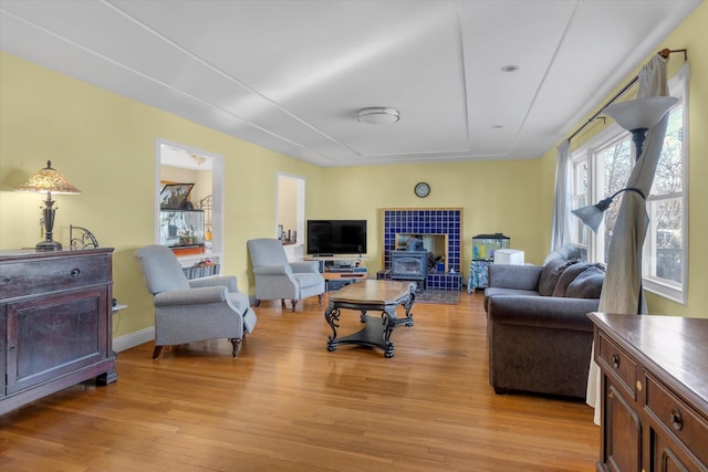 living area featuring a wood stove, light wood-style flooring, and baseboards