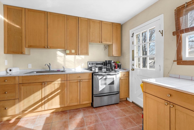 kitchen with light tile patterned floors, light countertops, stainless steel electric range, and a sink