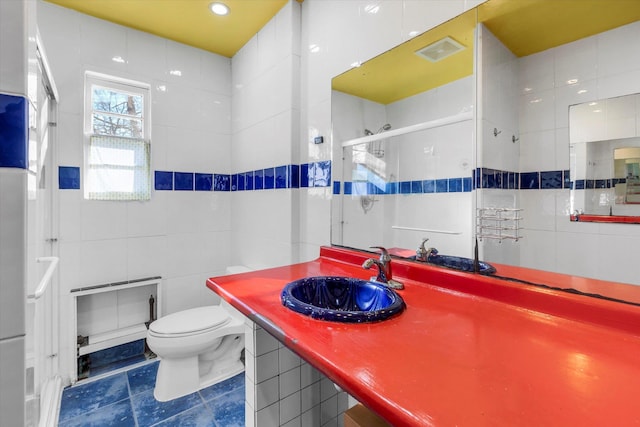 bathroom with tile walls, visible vents, toilet, a stall shower, and vanity