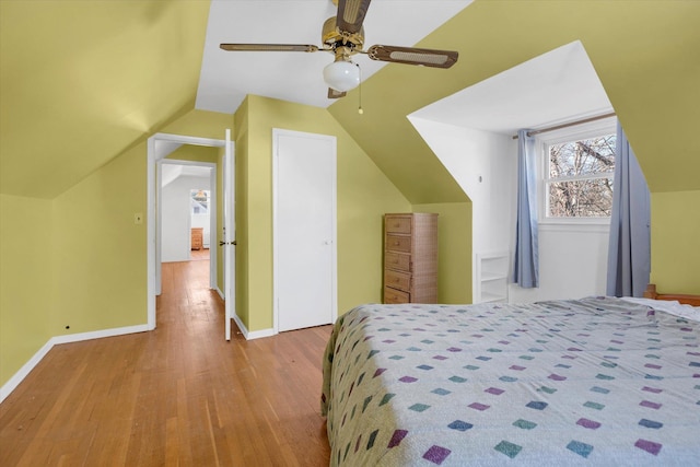 bedroom featuring wood finished floors, a ceiling fan, baseboards, vaulted ceiling, and a closet