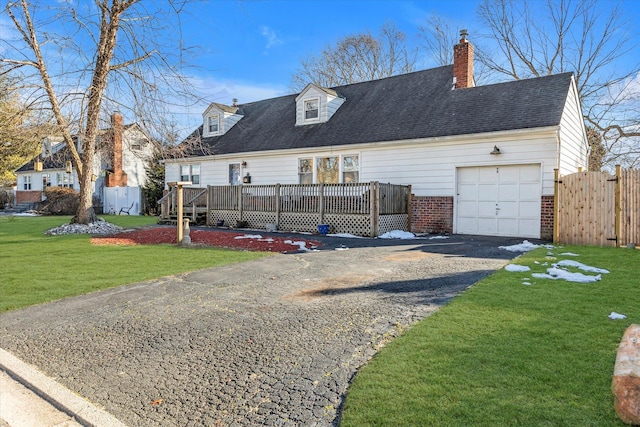 cape cod home with brick siding, an attached garage, a front yard, fence, and driveway