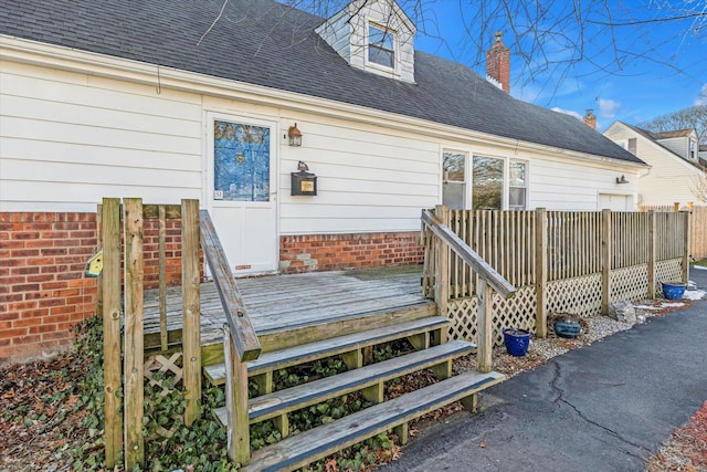 exterior space featuring roof with shingles and a wooden deck