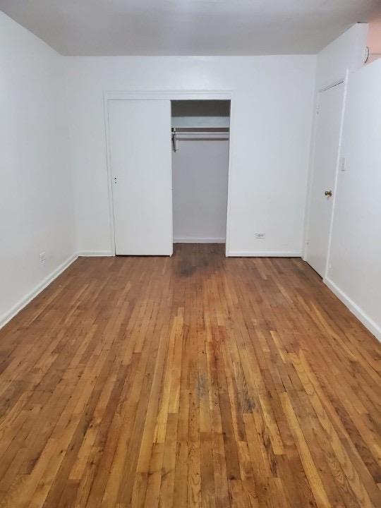 unfurnished bedroom featuring a closet, wood finished floors, and baseboards