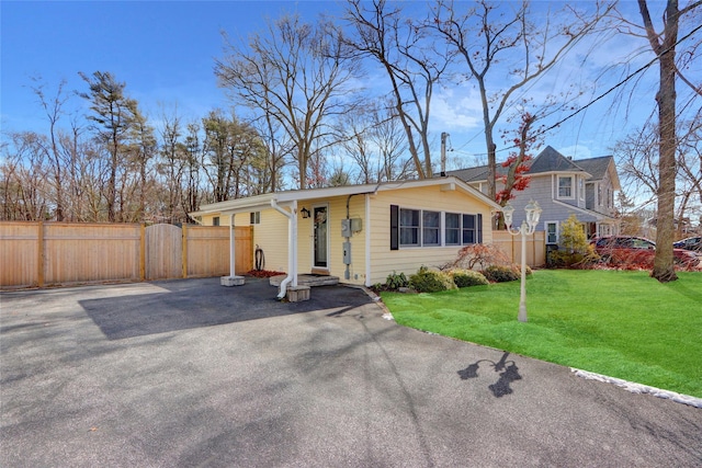 view of front of home with a gate, fence, driveway, and a front lawn