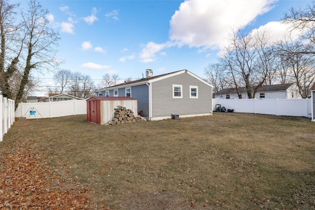 rear view of house featuring a yard and a storage shed