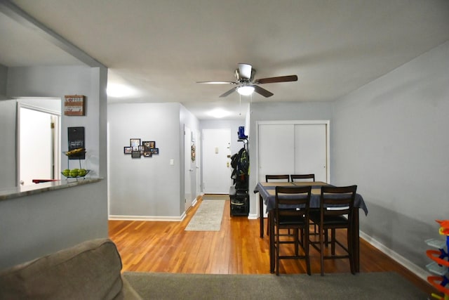 dining space with a ceiling fan, baseboards, and wood finished floors