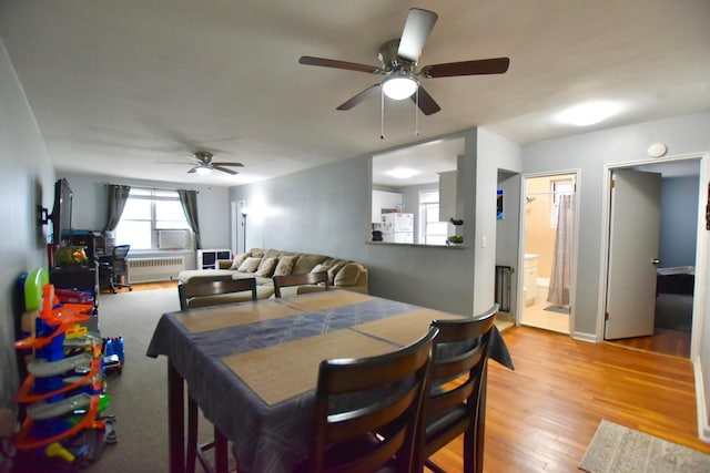 dining space with radiator, ceiling fan, and light wood-style flooring