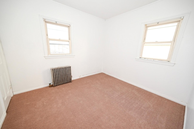 spare room featuring baseboards, radiator heating unit, and light colored carpet