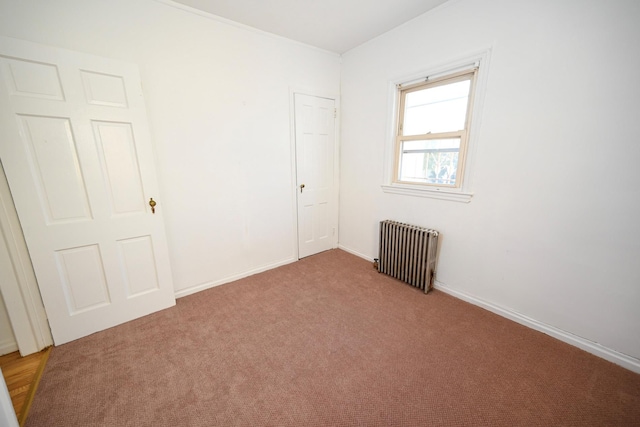 carpeted spare room with radiator and baseboards