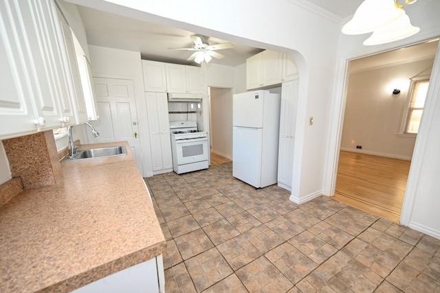 kitchen with arched walkways, light countertops, white cabinets, a sink, and white appliances