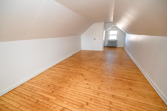 bonus room featuring lofted ceiling, light wood finished floors, radiator heating unit, and baseboards