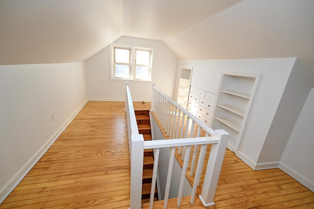 additional living space with lofted ceiling, built in features, light wood-style flooring, and baseboards