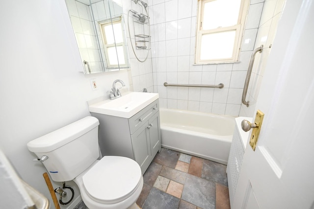 bathroom featuring toilet, stone tile floors, bathing tub / shower combination, and vanity