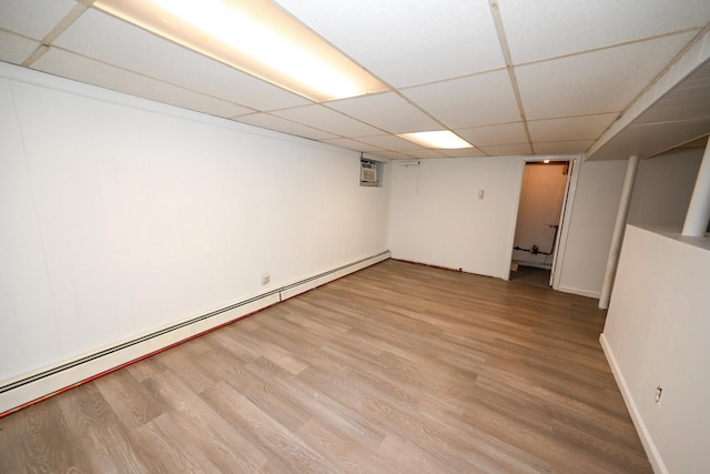 finished basement with baseboards, a drop ceiling, baseboard heating, and wood finished floors