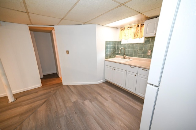 kitchen with a sink, white cabinets, light countertops, freestanding refrigerator, and light wood finished floors