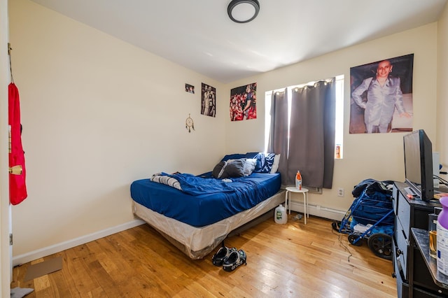 bedroom featuring hardwood / wood-style flooring and a baseboard heating unit