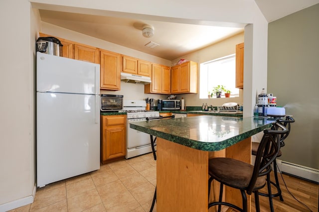 kitchen with a kitchen breakfast bar, white appliances, light tile patterned floors, sink, and a baseboard heating unit