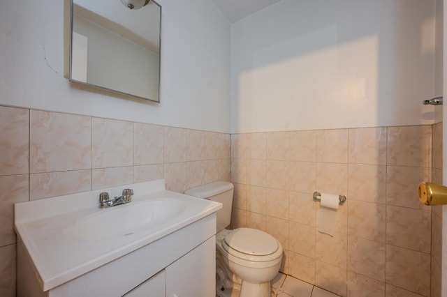 bathroom with tile walls, toilet, and vanity