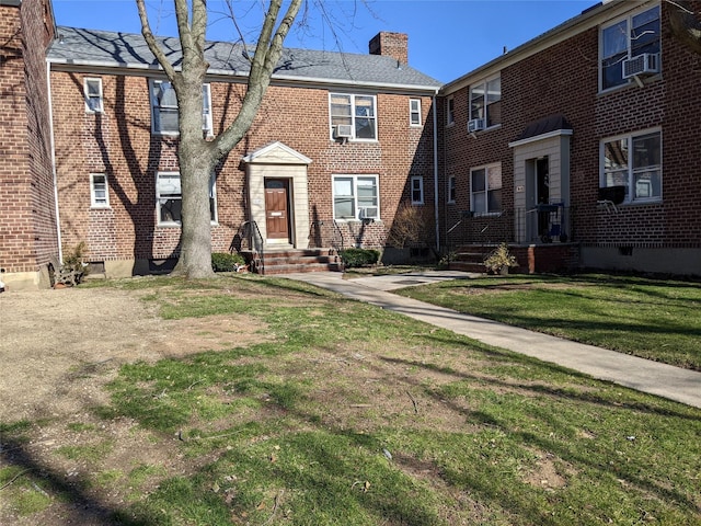 view of front of home with cooling unit and a front lawn