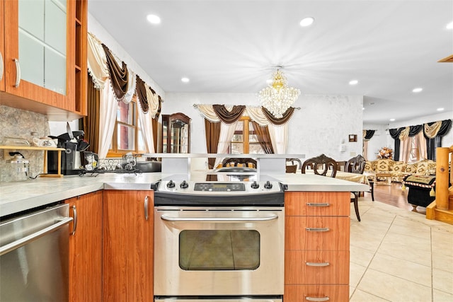 kitchen featuring light tile patterned floors, plenty of natural light, glass insert cabinets, stainless steel appliances, and light countertops