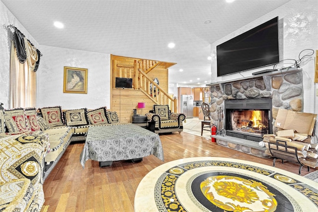 living room featuring stairs, recessed lighting, a fireplace, and wood finished floors