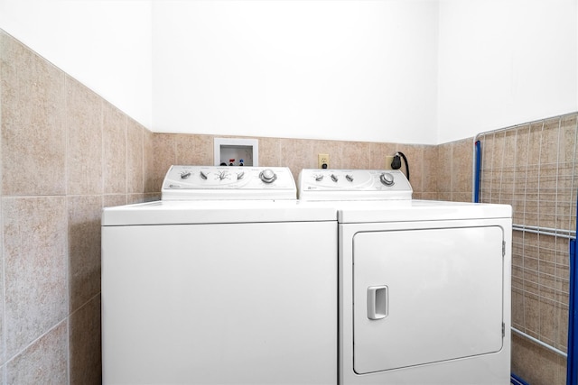 laundry room featuring laundry area, tile walls, and washing machine and clothes dryer