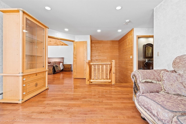 sitting room with wood walls, light wood-type flooring, and recessed lighting