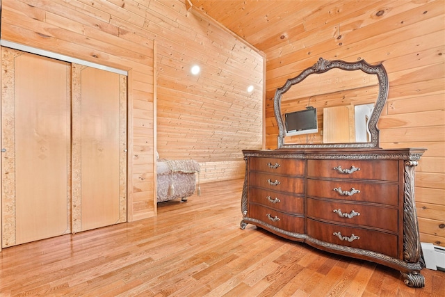 unfurnished bedroom featuring baseboard heating, wood walls, light wood-type flooring, and wooden ceiling