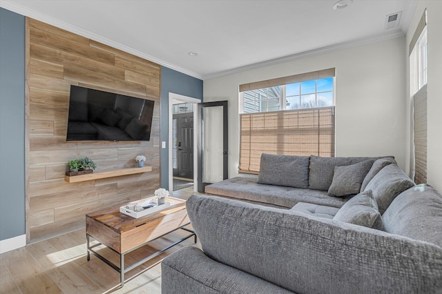 living room with ornamental molding, visible vents, wood finished floors, and a wealth of natural light