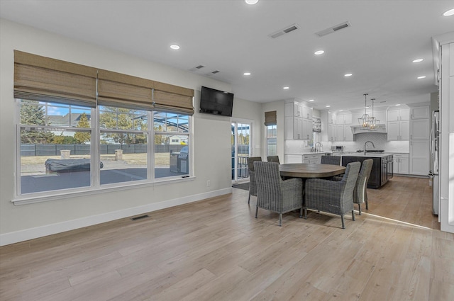 dining area featuring baseboards, light wood finished floors, and visible vents