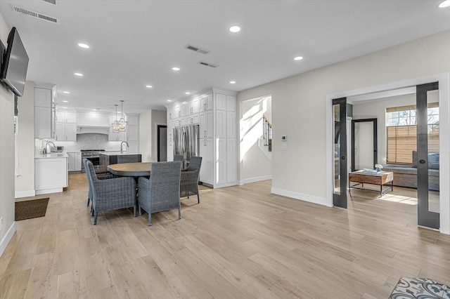 dining area with light wood-style flooring, visible vents, and recessed lighting