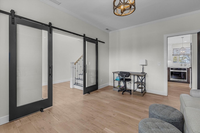 home office with crown molding, an inviting chandelier, light wood-type flooring, and a barn door