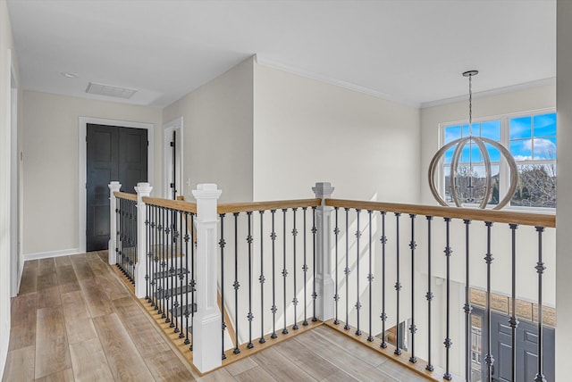 hallway featuring baseboards, crown molding, wood finished floors, and an upstairs landing