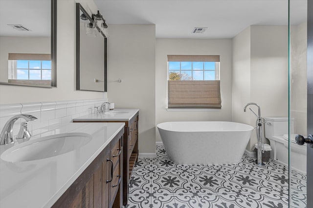 bathroom featuring tile patterned floors, visible vents, a freestanding tub, and a healthy amount of sunlight