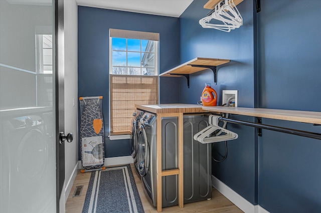 washroom featuring washing machine and clothes dryer, baseboards, laundry area, and wood finished floors