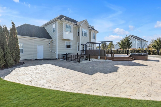 back of property featuring a patio area, fence, a wooden deck, a hot tub, and a pergola