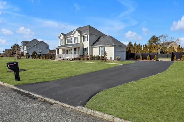 view of front of home with fence, a front yard, driveway, covered porch, and a garage