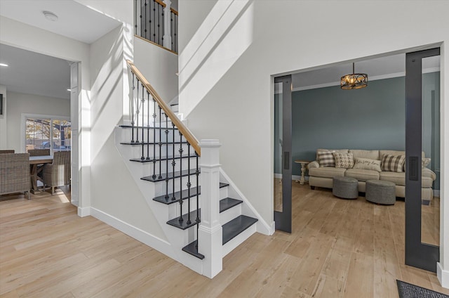 stairway with baseboards, wood finished floors, and a high ceiling