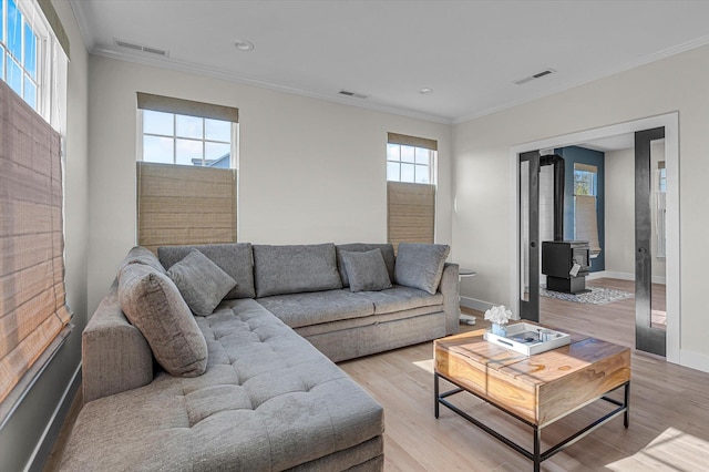 living room featuring light wood finished floors, visible vents, and a wood stove