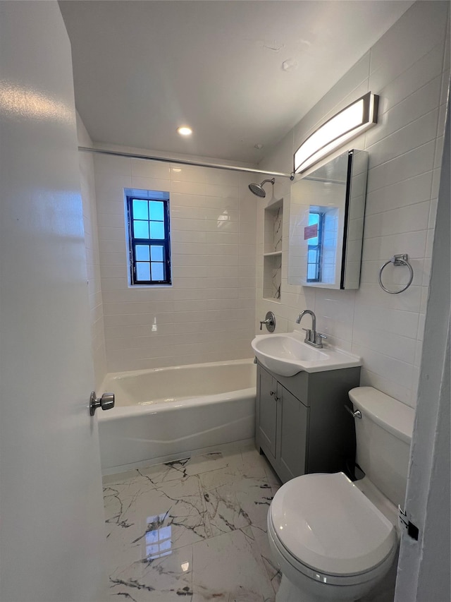 full bathroom with tile walls, vanity, tiled shower / bath, and toilet