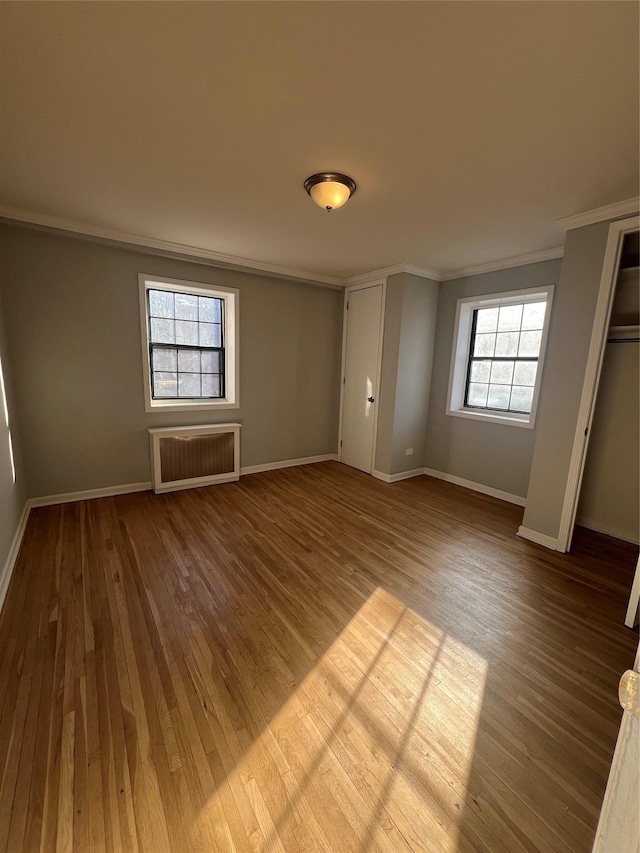 unfurnished bedroom featuring ornamental molding, hardwood / wood-style floors, and radiator heating unit