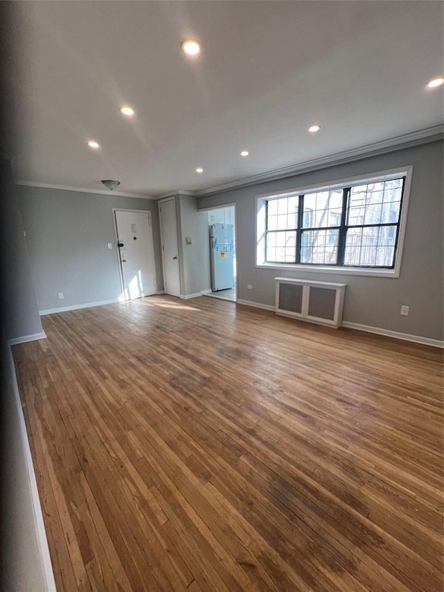 unfurnished living room featuring hardwood / wood-style flooring and crown molding