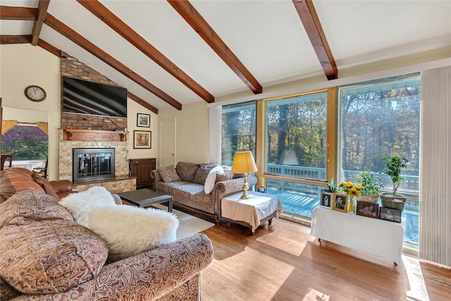 living room featuring vaulted ceiling with beams, light wood-style floors, and a fireplace