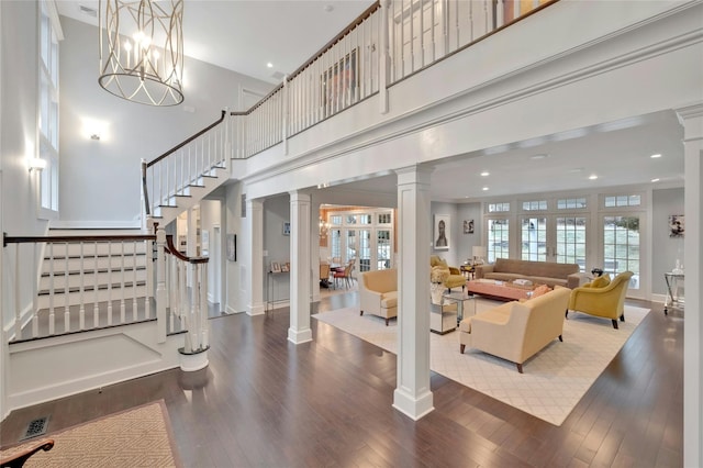 living area with hardwood / wood-style floors, a high ceiling, decorative columns, plenty of natural light, and stairs