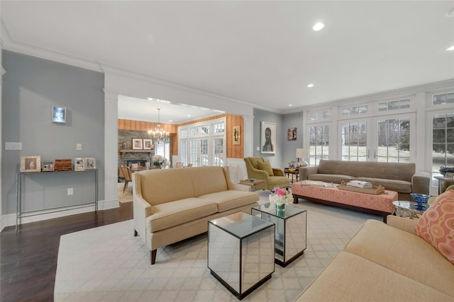 living area featuring wood finished floors, decorative columns, a healthy amount of sunlight, and ornamental molding