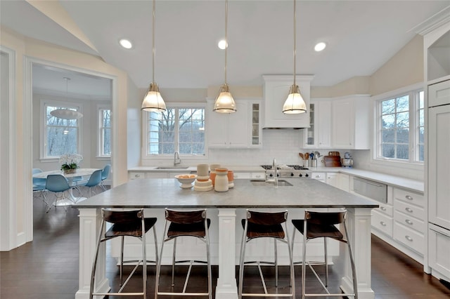 kitchen with a sink, glass insert cabinets, dark wood-style flooring, and vaulted ceiling