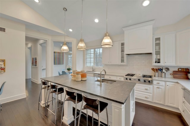 kitchen with a sink, lofted ceiling, a breakfast bar, and stainless steel gas cooktop