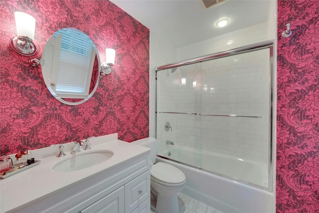 bathroom featuring toilet, wallpapered walls, vanity, and bath / shower combo with glass door