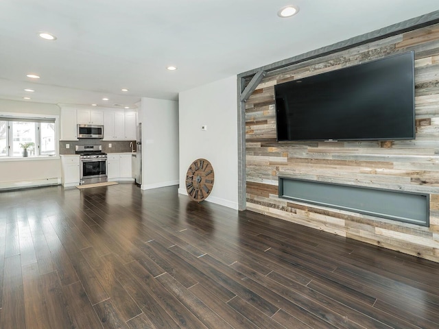 unfurnished living room featuring a baseboard radiator, dark wood-type flooring, and a fireplace