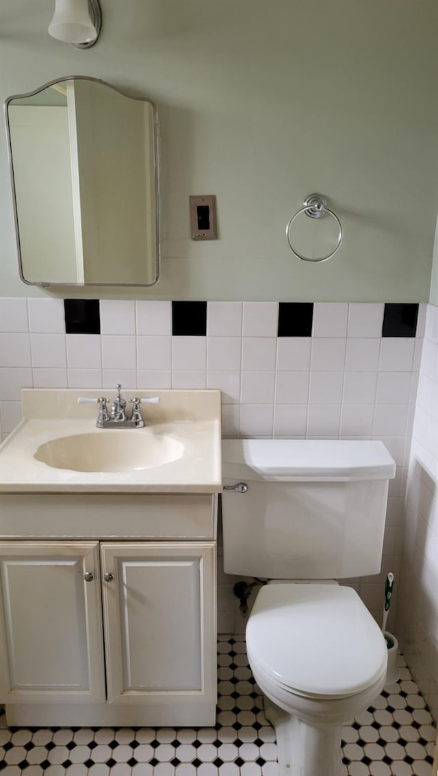 half bathroom featuring tile walls, toilet, and vanity